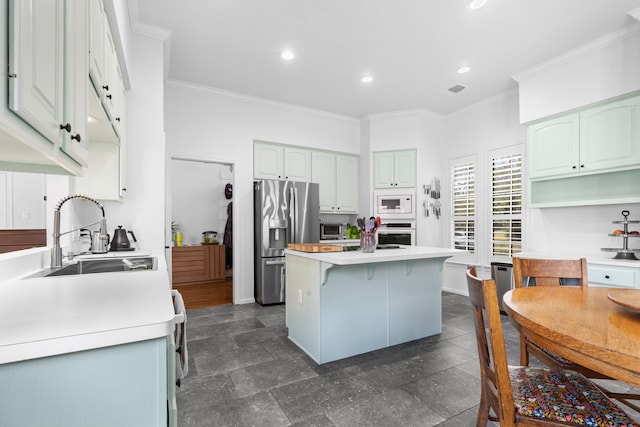 kitchen featuring a breakfast bar, stainless steel appliances, crown molding, and a sink