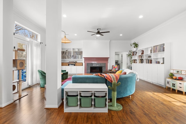 living area with wood finished floors, baseboards, a fireplace, recessed lighting, and crown molding