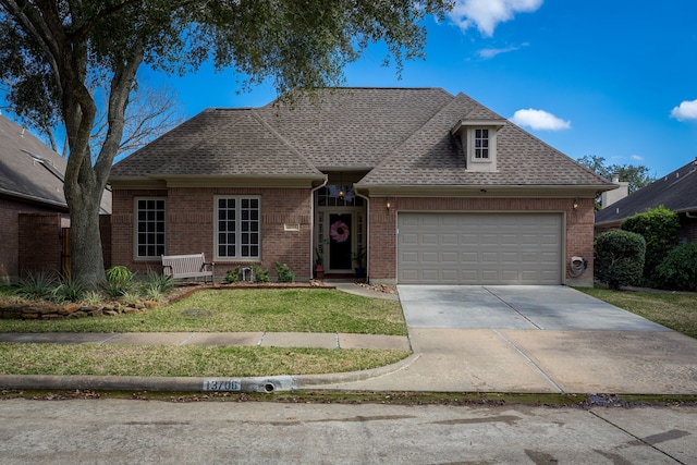 view of front facade with roof with shingles, concrete driveway, a front lawn, a garage, and brick siding