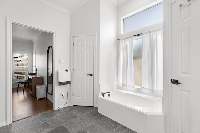 bathroom with crown molding, stone finish floor, a garden tub, and baseboards