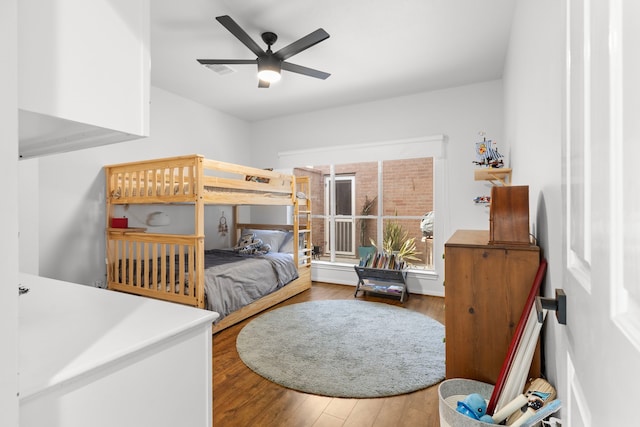 bedroom with ceiling fan, visible vents, and wood finished floors