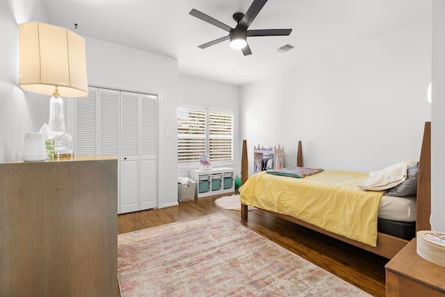 bedroom featuring a ceiling fan, wood finished floors, visible vents, and a closet