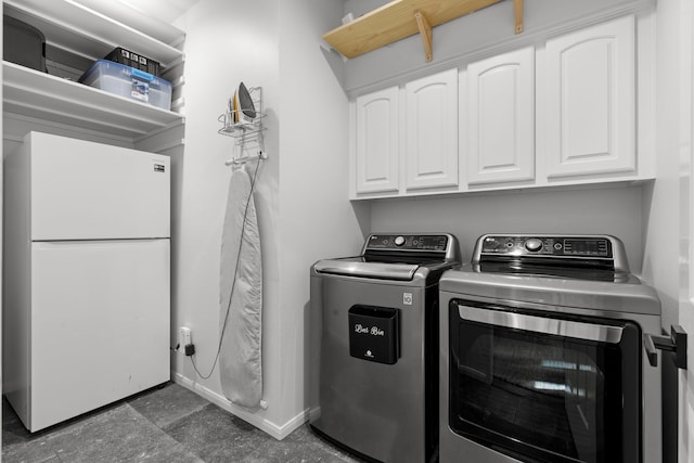 clothes washing area featuring washer and dryer, baseboards, and cabinet space