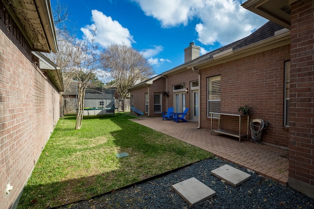 view of yard with a patio, a trampoline, and a fenced backyard