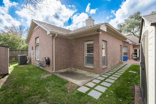 view of property exterior with cooling unit, a yard, a chimney, a patio area, and brick siding