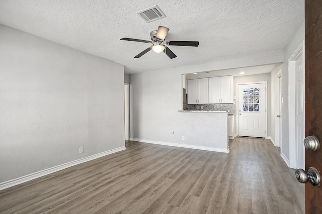 unfurnished living room with ceiling fan, wood finished floors, visible vents, and baseboards