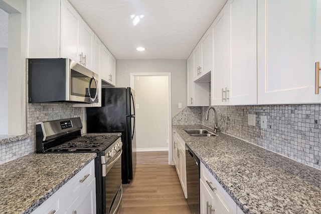 kitchen featuring light wood-style flooring, appliances with stainless steel finishes, white cabinets, and a sink