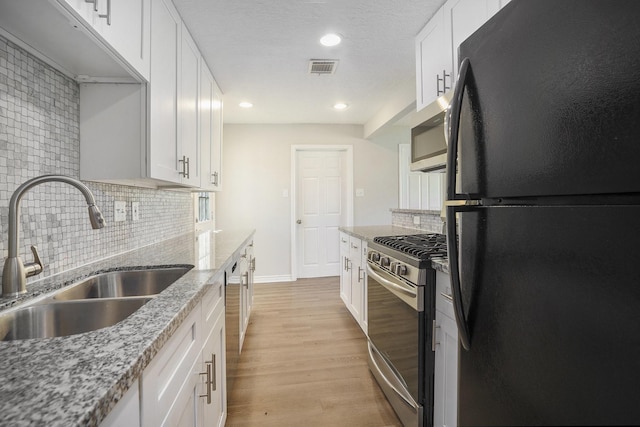 kitchen featuring light wood-type flooring, visible vents, a sink, stainless steel appliances, and white cabinets