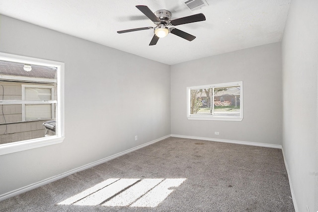 empty room with visible vents, baseboards, a ceiling fan, and carpet flooring