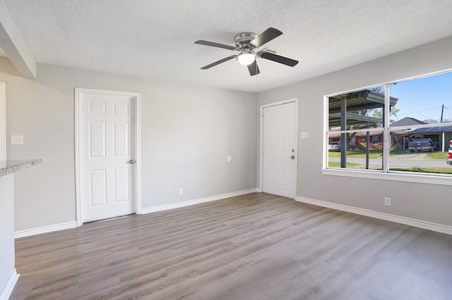 spare room featuring wood finished floors, baseboards, and a textured ceiling