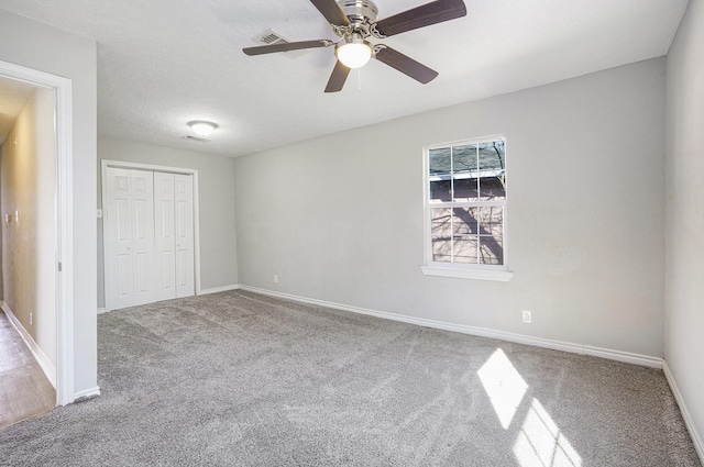 unfurnished bedroom featuring a closet, carpet floors, baseboards, and ceiling fan