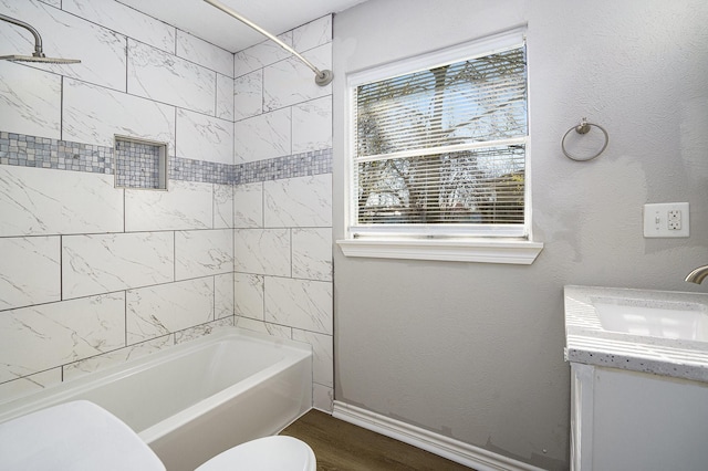 bathroom with toilet, wood finished floors, tub / shower combination, baseboards, and vanity