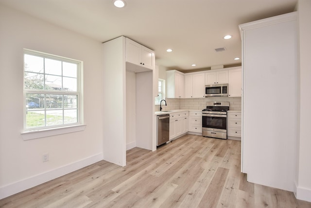 kitchen featuring recessed lighting, a sink, decorative backsplash, stainless steel appliances, and light wood-style floors