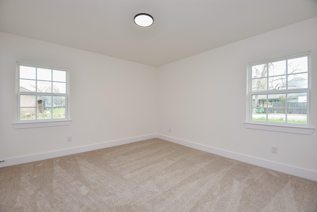 empty room featuring light colored carpet and baseboards