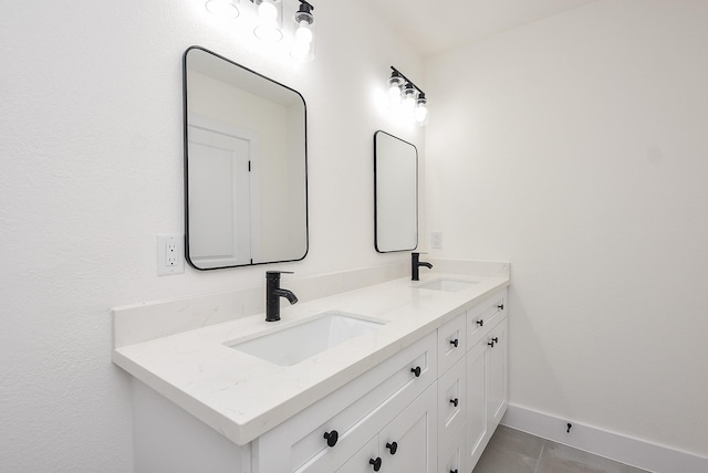 bathroom featuring a sink, baseboards, double vanity, and tile patterned flooring