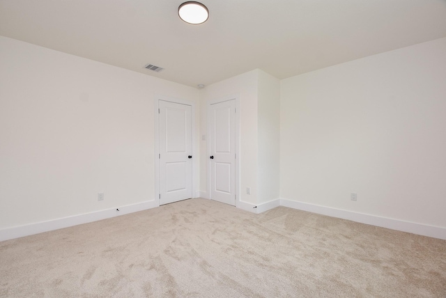 carpeted spare room with visible vents and baseboards