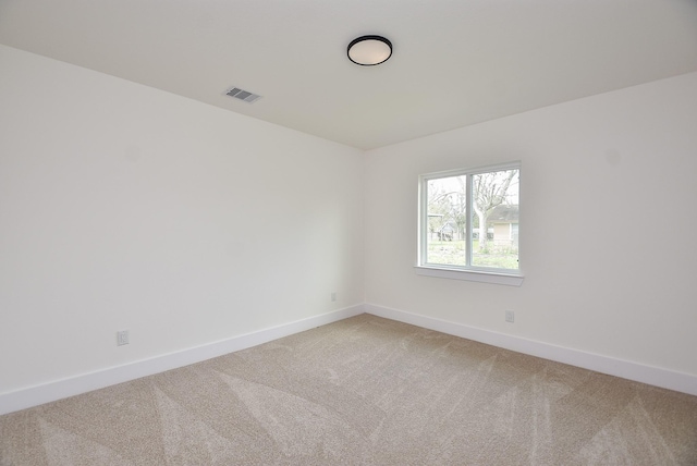 spare room with baseboards, visible vents, and light carpet