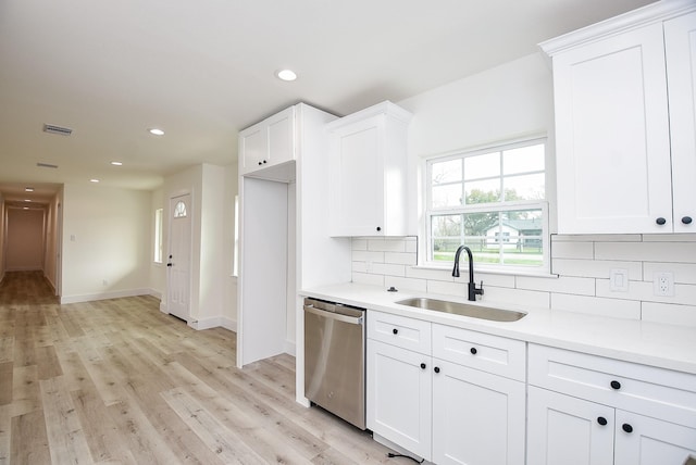 kitchen with visible vents, a sink, decorative backsplash, dishwasher, and light wood-type flooring