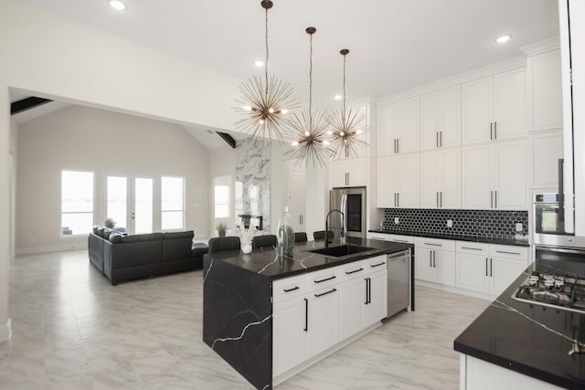 kitchen featuring dark countertops, plenty of natural light, appliances with stainless steel finishes, a notable chandelier, and a sink