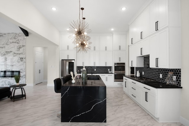 kitchen featuring a notable chandelier, marble finish floor, a sink, appliances with stainless steel finishes, and hanging light fixtures