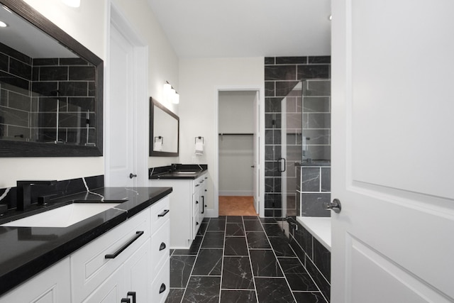 full bath featuring two vanities, tiled shower, marble finish floor, and a sink