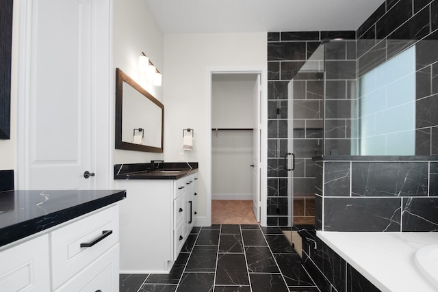 full bath featuring vanity, baseboards, and a stall shower