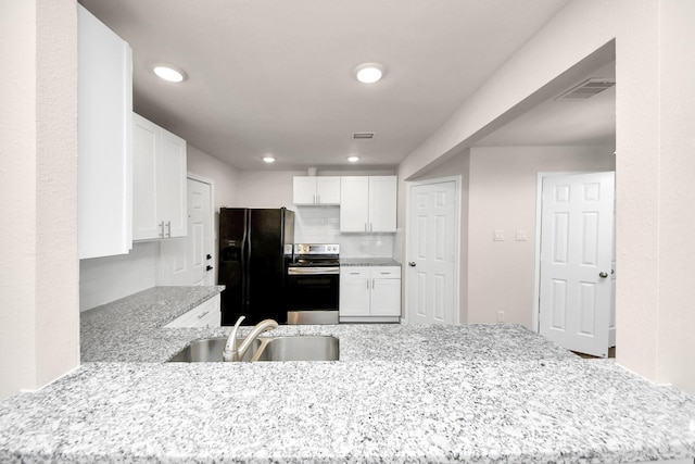 kitchen featuring light stone counters, stainless steel electric stove, a sink, black fridge with ice dispenser, and white cabinetry