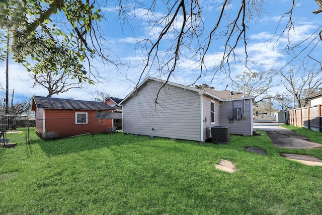 exterior space featuring cooling unit, fence, and a lawn