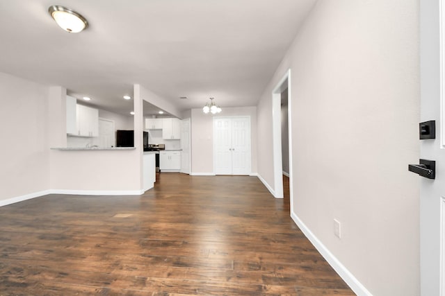 unfurnished living room with recessed lighting, baseboards, dark wood-type flooring, and a chandelier