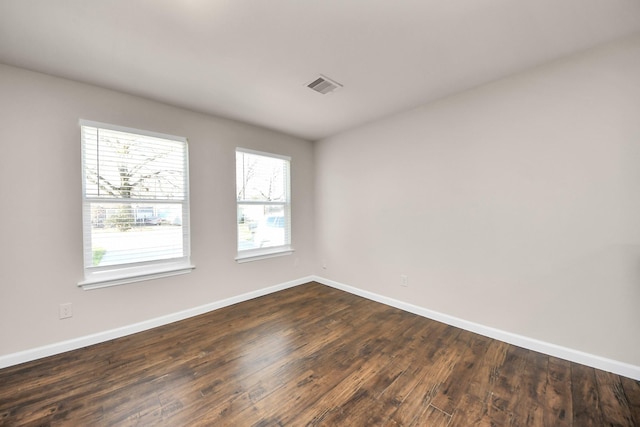 unfurnished room with dark wood finished floors, visible vents, and baseboards