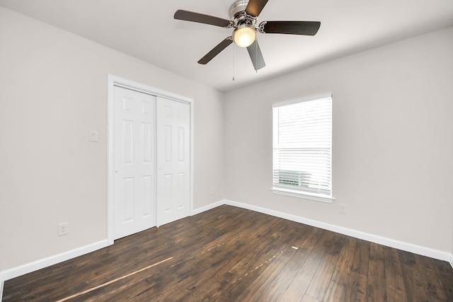 unfurnished bedroom featuring dark wood-type flooring, baseboards, a closet, and ceiling fan