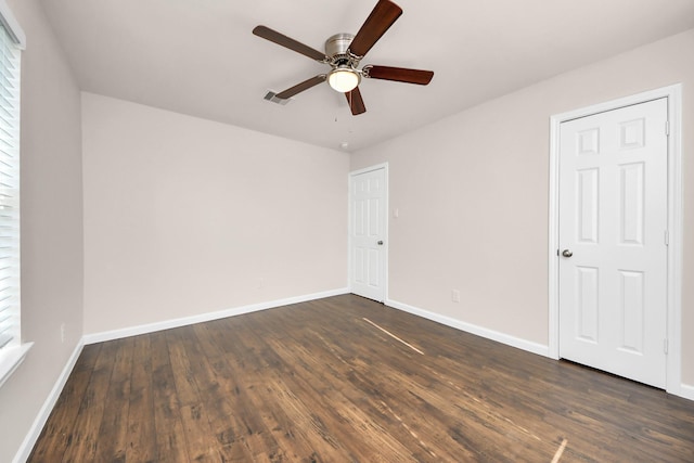 unfurnished room featuring visible vents, baseboards, dark wood-style flooring, and ceiling fan