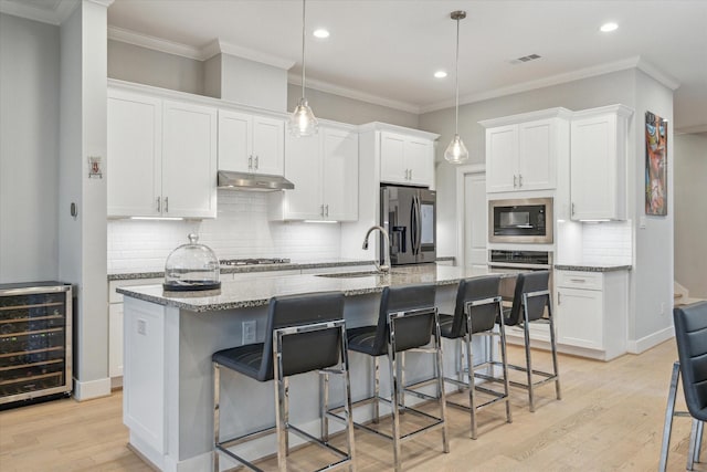 kitchen featuring under cabinet range hood, wine cooler, white cabinets, stainless steel appliances, and a sink