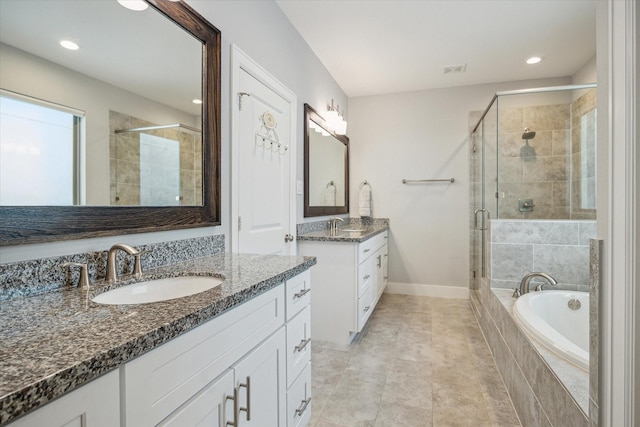 bathroom featuring two vanities, a stall shower, a sink, baseboards, and a bath