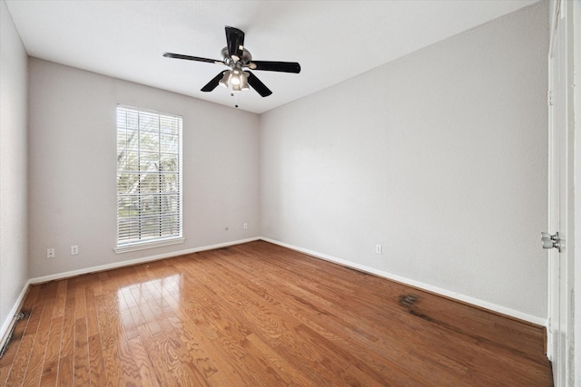 empty room with baseboards, wood finished floors, and a ceiling fan