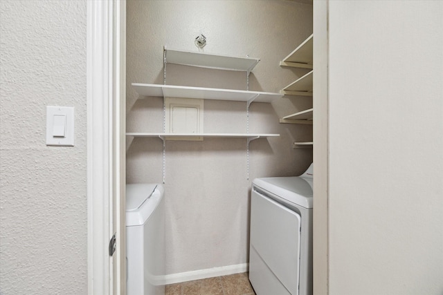 washroom featuring washer and dryer, baseboards, laundry area, and a textured wall