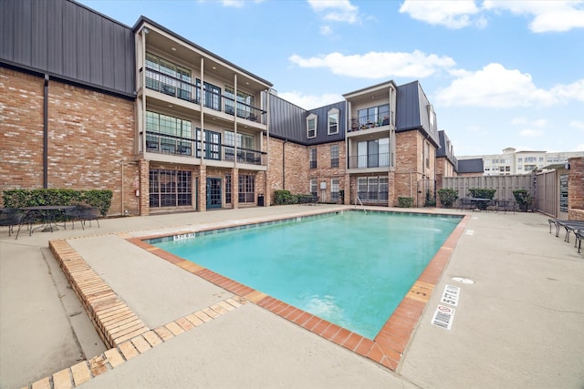 pool with a patio area and fence