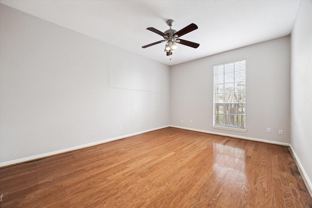 unfurnished room with a ceiling fan, wood finished floors, and baseboards