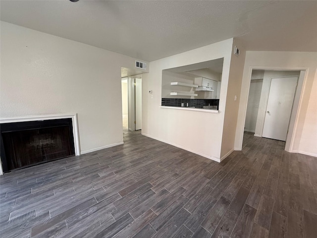 unfurnished living room with visible vents, a fireplace, dark wood-type flooring, and baseboards