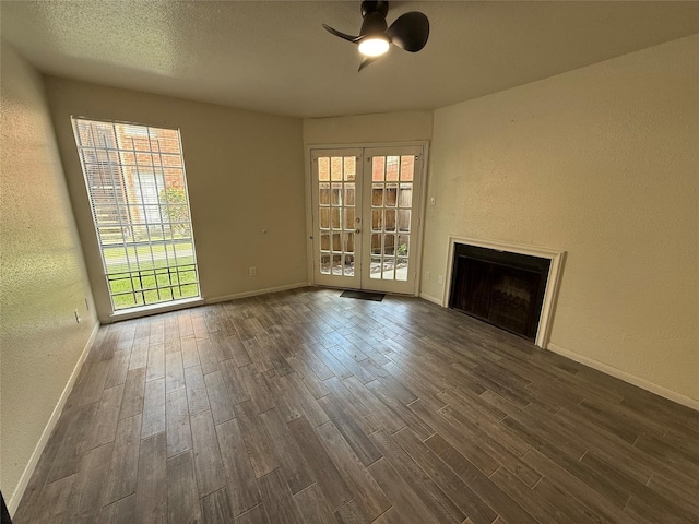 unfurnished living room with a fireplace, dark wood-style floors, and a healthy amount of sunlight