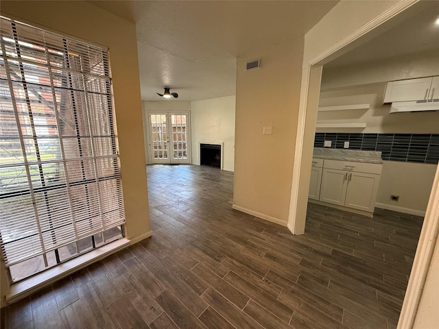 hall featuring visible vents, baseboards, and dark wood-style floors