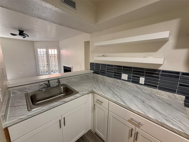 kitchen with visible vents, light countertops, white cabinets, a textured ceiling, and a sink