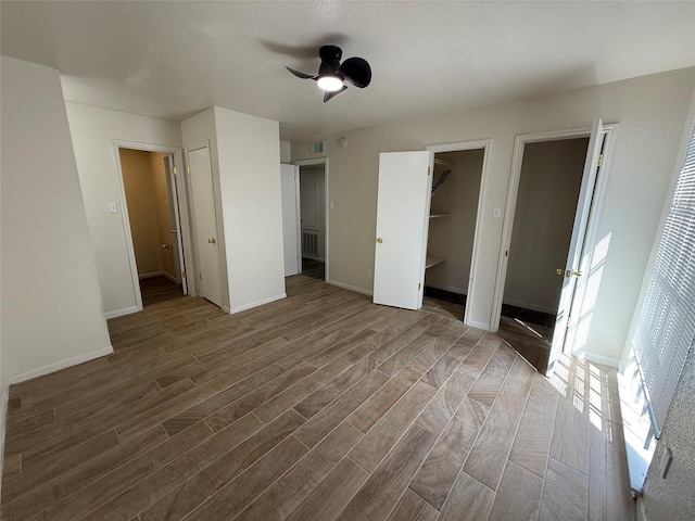 unfurnished bedroom featuring visible vents, ceiling fan, baseboards, and wood finished floors