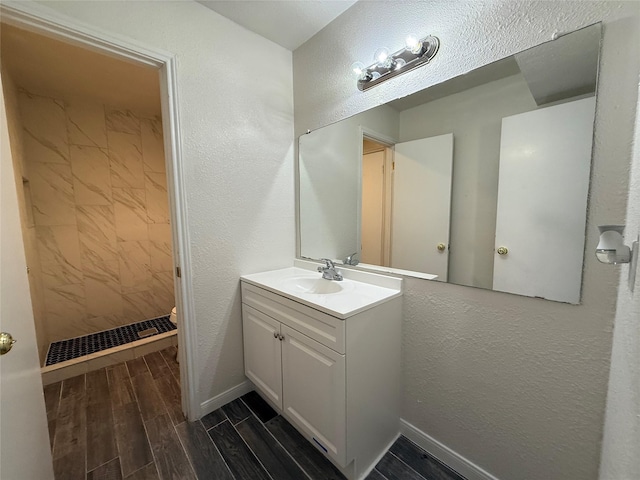 bathroom featuring vanity, a textured wall, baseboards, and wood tiled floor