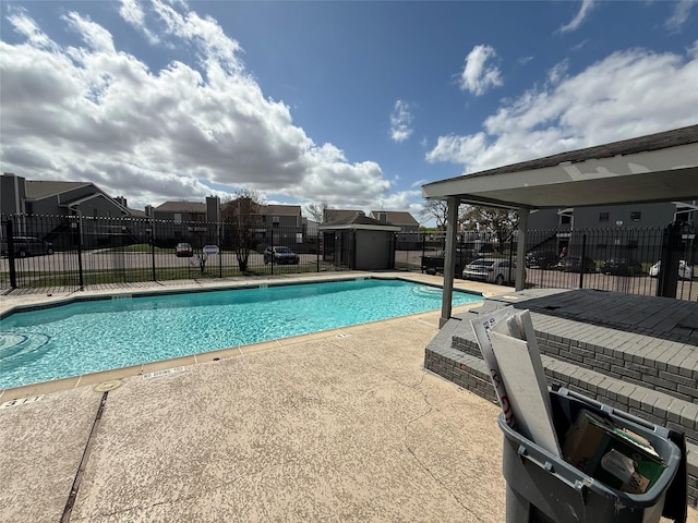 pool featuring a storage unit, a patio area, an outdoor structure, and fence