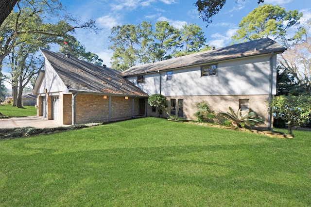 rear view of property with brick siding, a garage, a lawn, and driveway