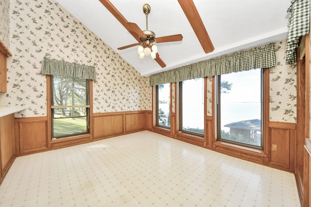 unfurnished room featuring wainscoting, wallpapered walls, lofted ceiling, and a ceiling fan