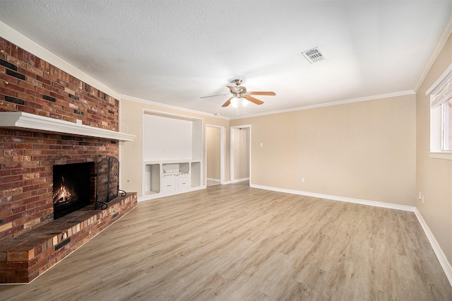 unfurnished living room with visible vents, a textured ceiling, a brick fireplace, and wood finished floors