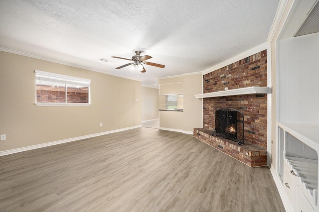 unfurnished living room with visible vents, a brick fireplace, light wood-style flooring, a textured ceiling, and a ceiling fan