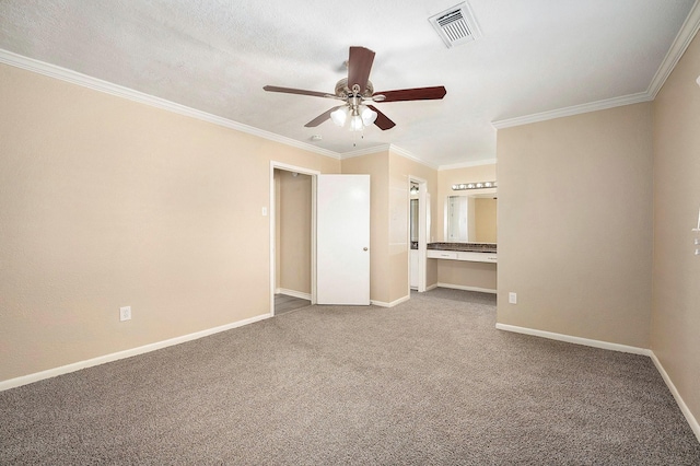 unfurnished bedroom with crown molding, carpet flooring, baseboards, and visible vents